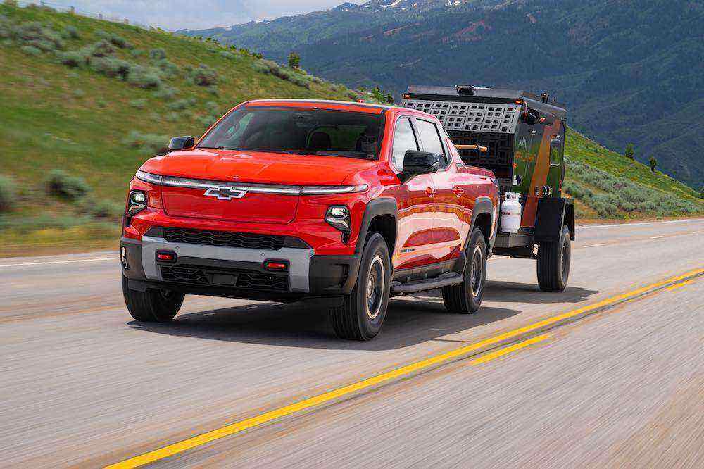 Front 3/4 view of Silverado EV Trail Boss towing a camper.