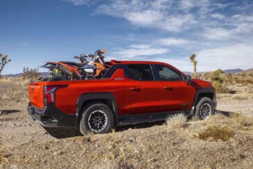 Dirt bikes in the bed of the 2026 Silverado EV in Habanero Orange, demonstrating the length of the bed with the Midgate down.