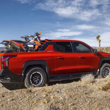 Dirt bikes in the bed of the 2026 Silverado EV in Habanero Orange, demonstrating the length of the bed with the Midgate down.
