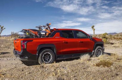 Dirt bikes in the bed of the 2026 Silverado EV in Habanero Orange, demonstrating the length of the bed with the Midgate down.
